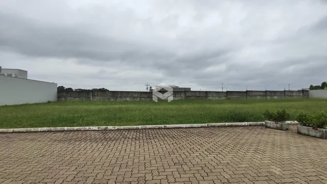 Vista externa de um terreno com muro e gramado verde.