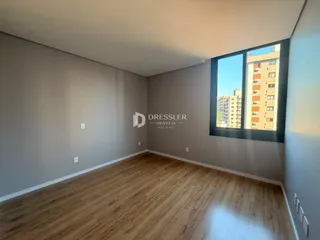 Uma sala de estar com piso de madeira clara e grande janela.