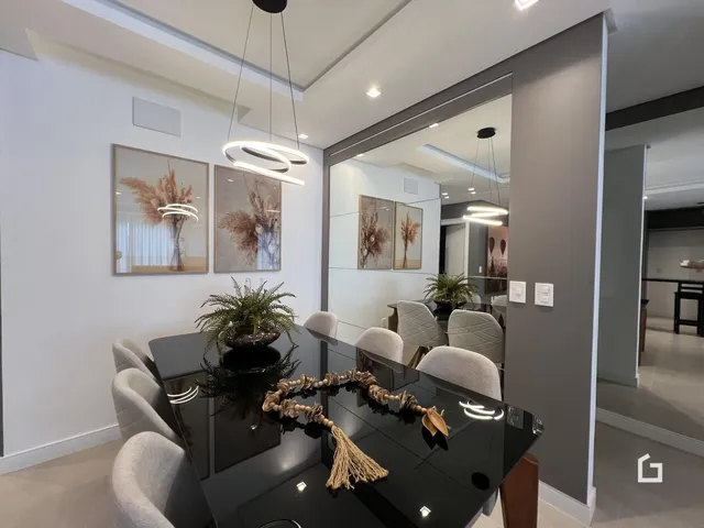 A sala de jantar apresenta uma mesa de vidro grande e cadeiras claras.