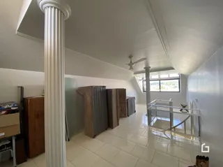 Corredor interno com piso de cerâmica e colunas brancas.