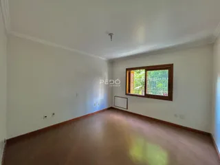 Ambiente interno de uma sala com piso de madeira e janela.