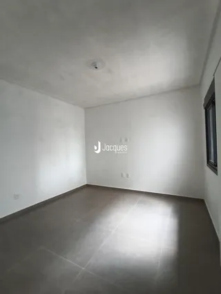 Interior de uma sala com paredes brancas e piso cinza claro.