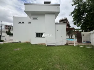 Fachada de uma residência branca com jardim e piscina em Lajeado.