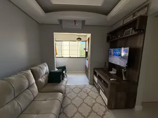 Sala de estar com sofá e painel de TV em um apartamento.