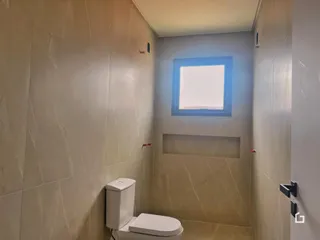 Banheiro com paredes revestidas em cerâmica clara.
