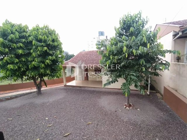 Vista externa da propriedade com árvores e área pavimentada.