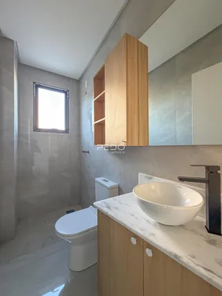 Banheiro moderno com bancada de mármore e armários de madeira clara.