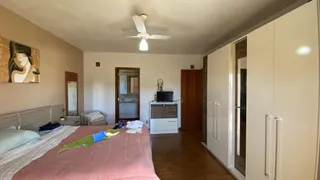 Um quarto com cama e armário em um imóvel com piso de madeira.