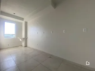 Uma vista interna de uma sala com paredes brancas e piso de cerâmica.