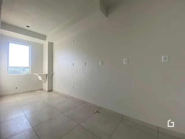Uma vista interna de uma sala com paredes brancas e piso de cerâmica.