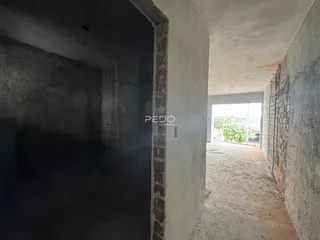 Passagem interna com paredes de alvenaria aparente em uma residência.