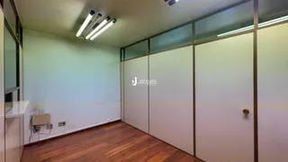 Vista interna de um ambiente com piso de madeira e divisórias de vidro.