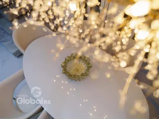 Mesa branca com centro de mesa decorativo em um ambiente iluminado.