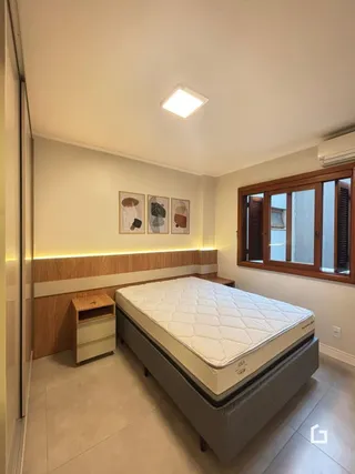 Quarto com cama e janela de madeira em um imóvel no Brasil.