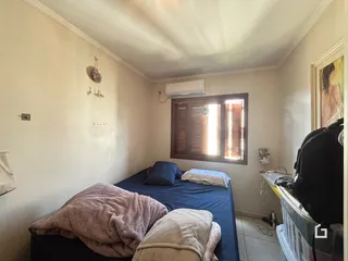Quarto com cama e janela de madeira no interior da residência.