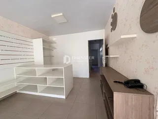 Ambiente interno de uma sala com paredes brancas e piso de cerâmica clara.