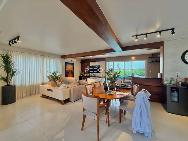 Sala de estar moderna com piso claro e vigas de madeira.