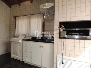 A cozinha apresenta armários brancos e bancada escura com revestimento de azulejos.