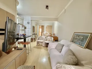 Sala de estar com sofá branco e piso de madeira clara.