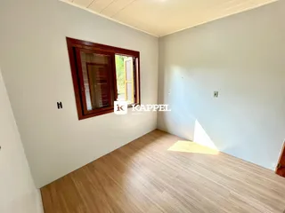 Uma sala de estar com piso de madeira clara e janela de madeira.