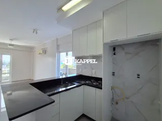 Uma cozinha moderna com armários brancos e bancadas escuras.