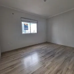 Foto interna de um cômodo com piso de madeira e paredes brancas.
