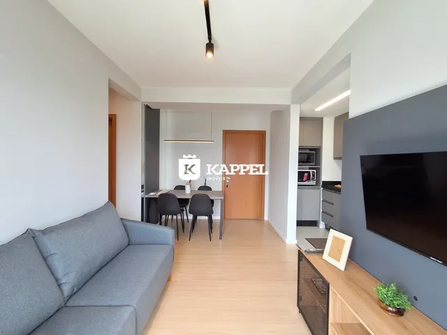 Sala de estar com sofá cinza e piso de madeira clara.