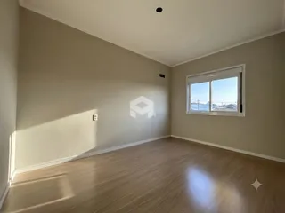 Vista interna de uma sala com piso de madeira e janela.
