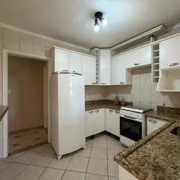 Foto de uma cozinha com armários brancos e bancadas.