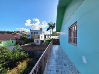 Fachada externa de uma residência com parede azul-turquesa e calçada de piso claro.