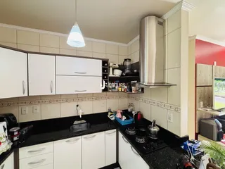 Foto da cozinha com armários brancos e bancada escura.