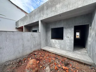 Foto de um corredor com paredes de concreto aparente e materiais de construção no chão.