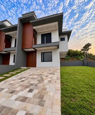 Fachada moderna de uma residência em Lajeado, Brasil, com paisagismo e calçada de pedras.