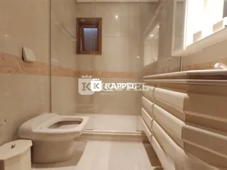 Foto interna de um banheiro com revestimento de azulejos claros e box de vidro.