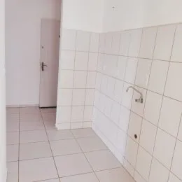 Vista de um corredor com paredes e piso de cerâmica branca.