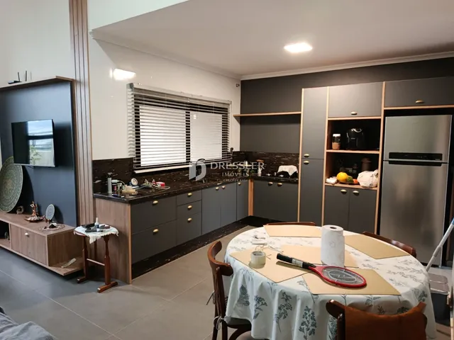 Interior de uma sala de estar com cozinha integrada em um imóvel no Brasil.