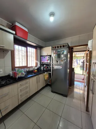 Vista interna de uma cozinha com armários de madeira e piso cerâmico.