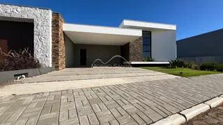 Fachada externa de uma casa moderna com revestimento de pedra e área de acesso pavimentada.
