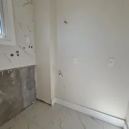 Parede interna com piso de mármore claro.