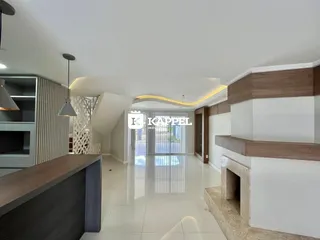 Vista interna de uma sala de estar com piso claro e iluminação moderna.
