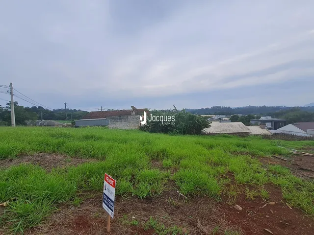 Vista de um campo gramado com estruturas ao fundo.