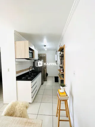 Cozinha com armários brancos e piso de cerâmica em ambiente claro.