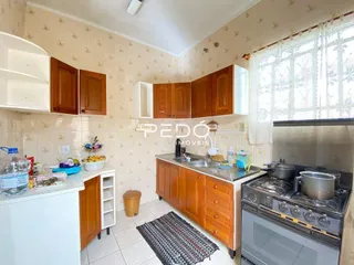 Foto interna de uma cozinha com armários de madeira e piso cerâmico.