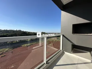 Vista da varanda mostrando um terreno seco e vegetação rasteira.