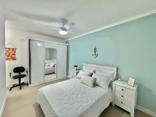 Quarto com cama de casal e guarda-roupa branco em ambiente claro.