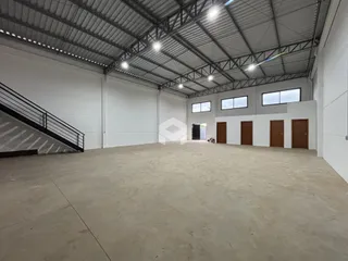 Espaço interno amplo com teto industrial e piso de concreto.