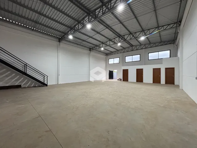 Espaço interno amplo com teto industrial e piso de concreto.