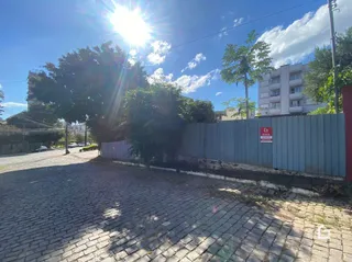 Vista da fachada de uma propriedade com cerca e área pavimentada.