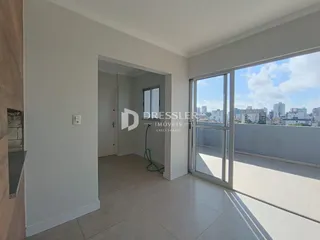 Interior de um ambiente com piso de cerâmica e porta de vidro que dá para uma varanda.