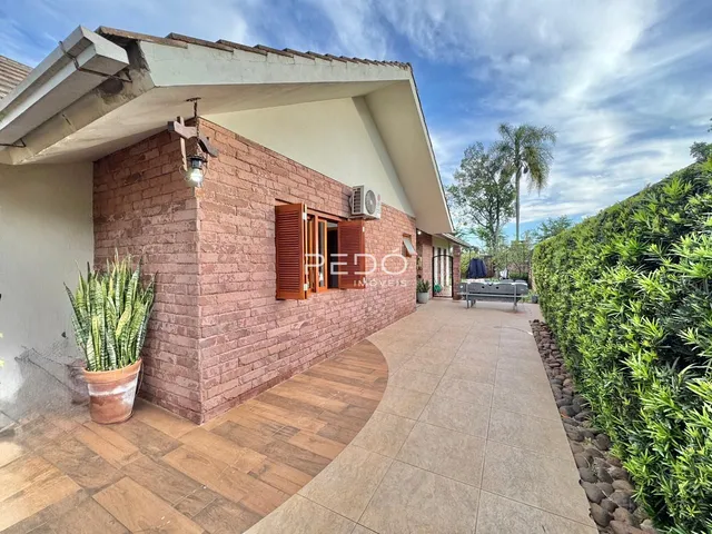 Fachada de casa em Lajeado, Brasil, com parede de tijolos aparentes e área externa pavimentada.